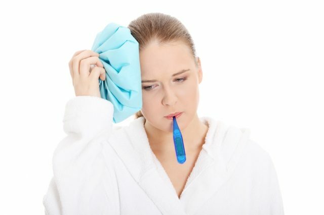 Een meisje met een thermometer in haar mond past een ijs-tegen-luchtbel toe
