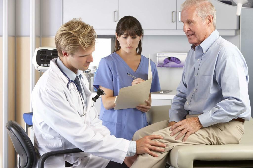 Der Arzt untersucht das Knie, bevor er eine Diagnose stellt